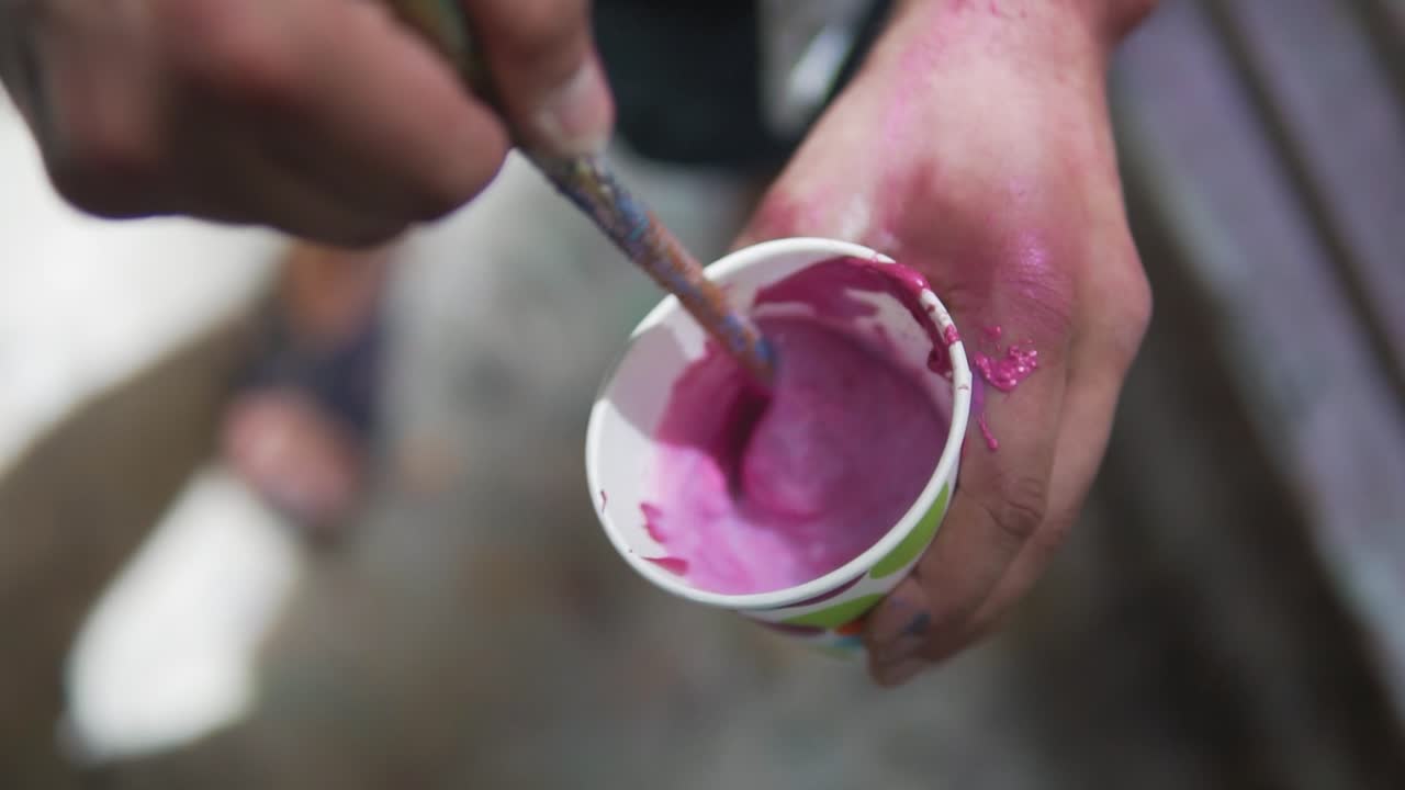 Close-up da mão de um artista misturando aquarela rosa para grafite.