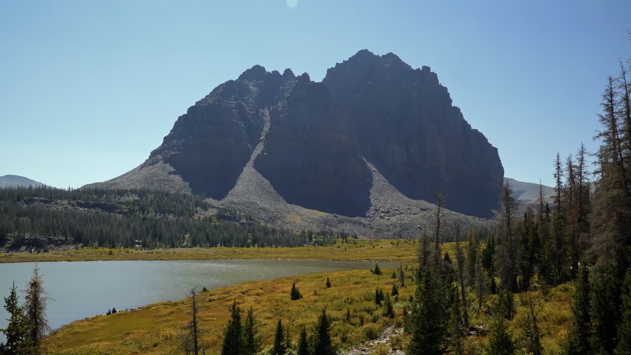 Stunning nature landscape tilting up shot of the incredible Red Castle Peak up a backpacking trail in the High Uinta National Forest between Utah and Wyoming with a fishing lake to the left