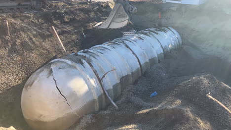 industrial excavator moves large fiberglass tank