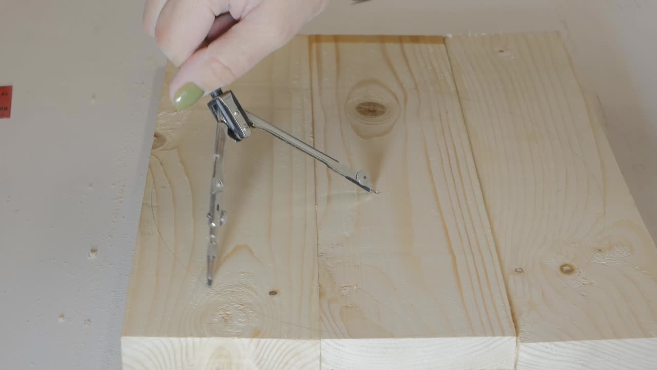 여성의 손은 바를 자르기 위해 나무 제품에 나침반으로 원을 그립니다.