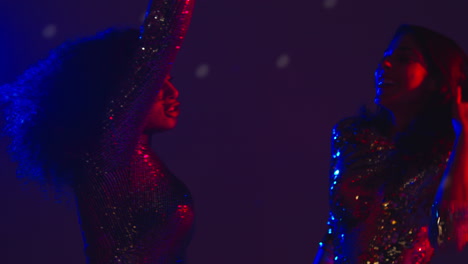 close up of two women in nightclub bar or disco dancing with falling gold confetti 1