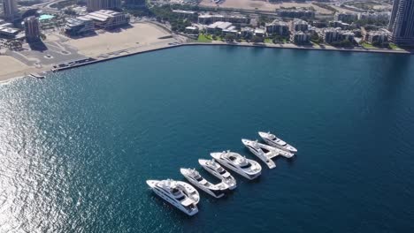 several yachts are positioned on the water to spell the word dubai, offering a unique perspective on luxury and tourism in the united arab emirates, with the cityscape in the background