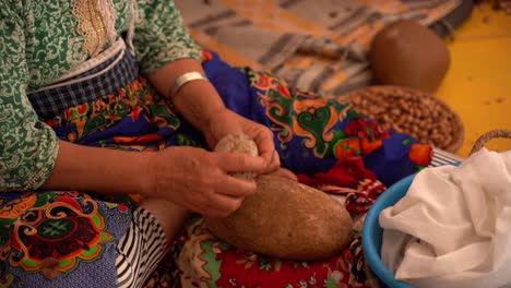 uma mulher destruindo as sementes usadas para produzir o óleo de argan, marrocos