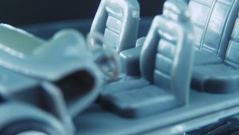 un diminuto modelo de esqueleto de muestra de metal de un coche en un soporte giratorio con luces de estudio, toma macro, vídeo de 4k, ruedas plateadas, neumáticos negros, puertas y ventanas, asientos de plástico