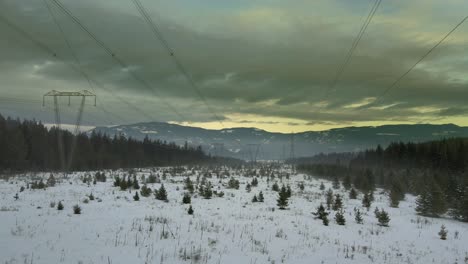 electricidad en movimiento: tiro de drones de cerca de líneas eléctricas en un paisaje montañoso nevado al atardecer
