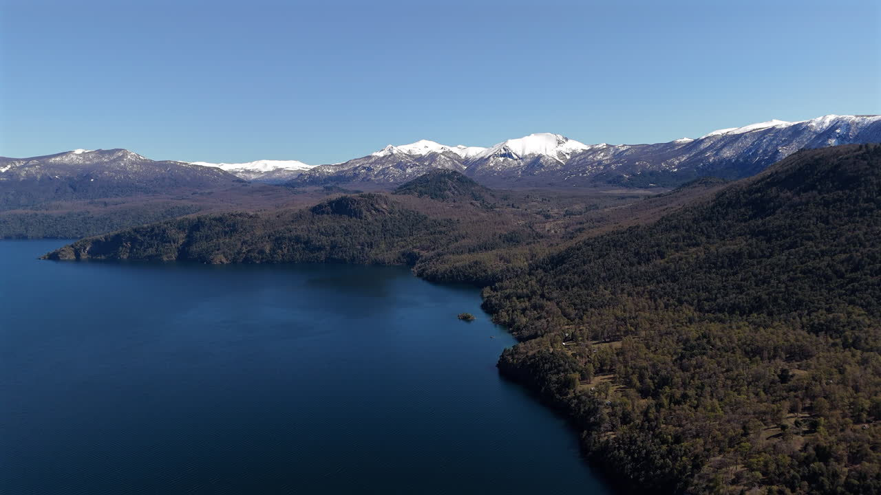 Vista aerea di un lago mozzafiato circondato da montagne innevate e una foresta lussureggiante