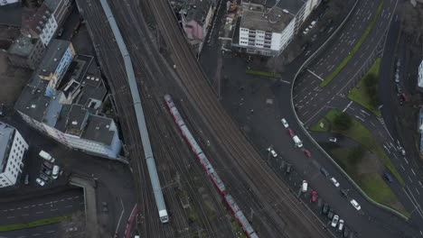 Top-down-footage-of-train-leaving-train-station.-Tracking-of-train-unit-driving-on-wide-multitrack-railway-line-in-city.-Cologne,-Germany