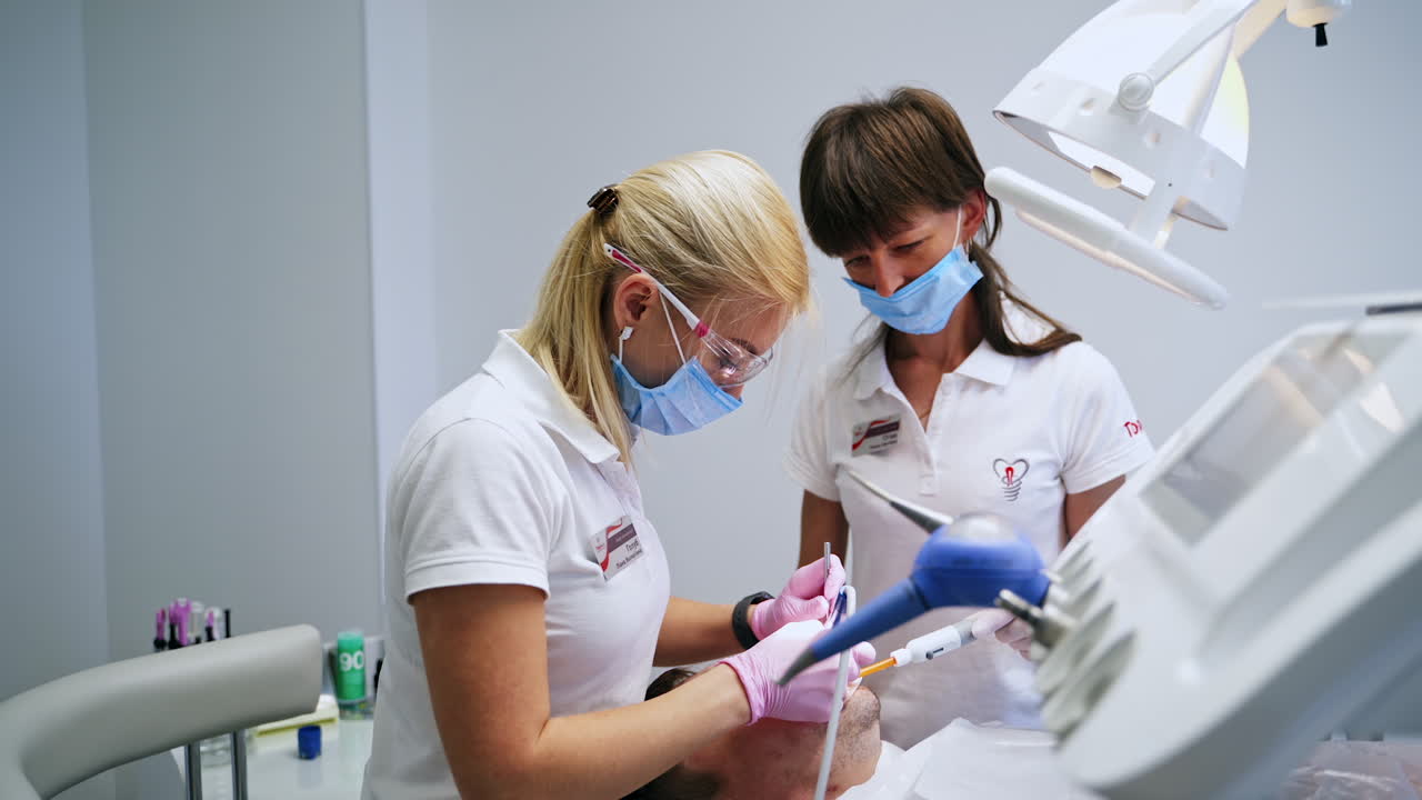 Female blonde dentist treating the teeth for the male patient. Dental care in the clinics.