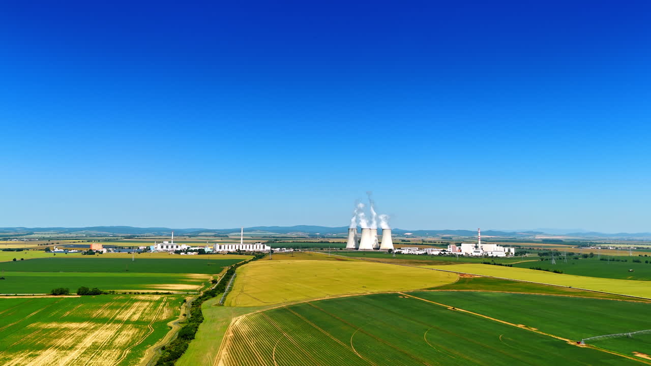 Flight over the green agricultural fields approaching industrial plant. Enterprise in the countryside of Slovakia