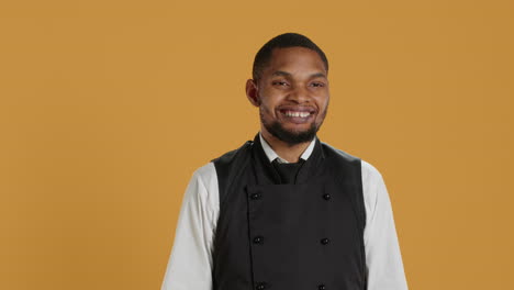 Restaurant-staff-showing-tablet-with-green-screen-against-yellow-background