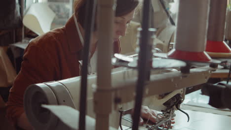 female shoemaker working with sewing machine in workshop