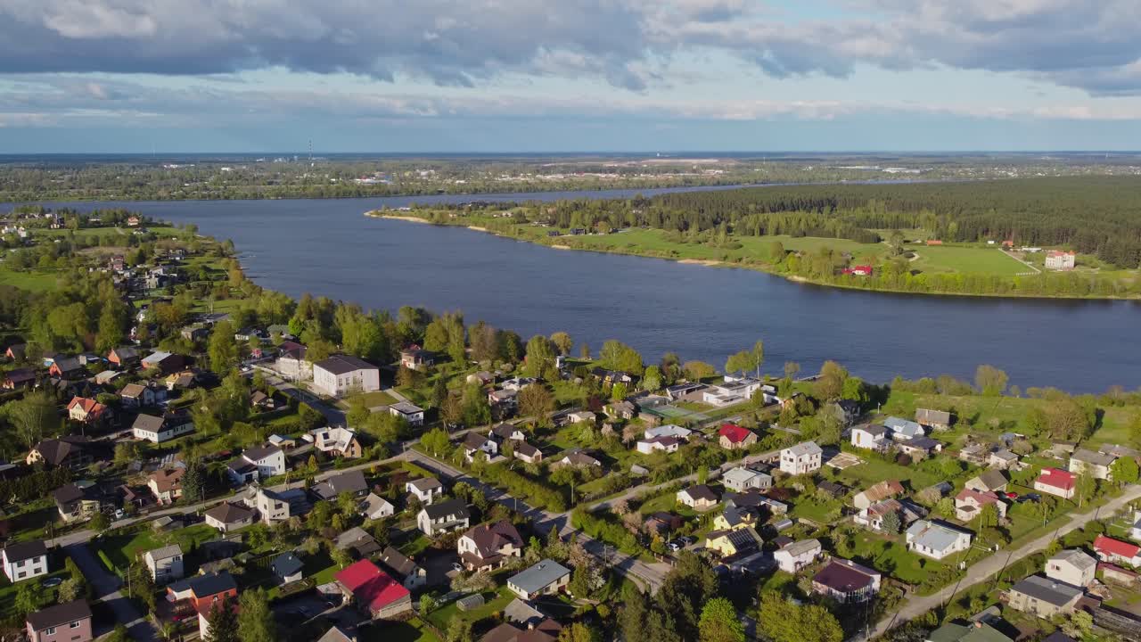 Katlakalns Spring Residential Area lies beside a wide river, surrounded by greenery and calm.