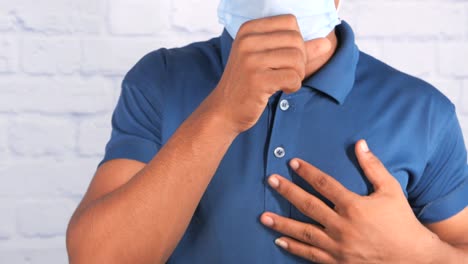 man coughing, wearing a mask