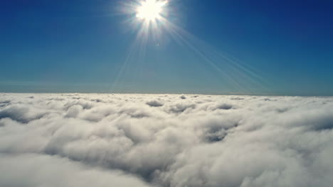 epic drone shot over white clouds with sunbeam and blue sky in background - high angle backwards flight in space