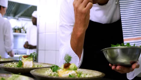 male chef garnishing appetizer plates at order station 4k