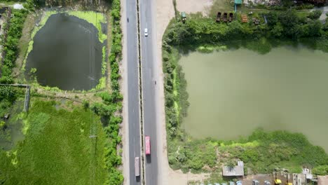 vehicles are moving from a beautiful road in dhaka city nearby a lake
