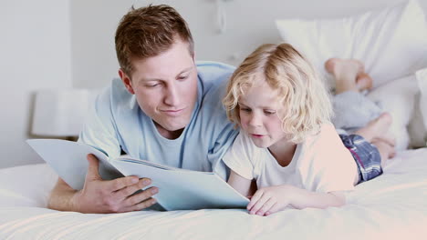 padre e hijo sonriendo mientras leen un libro