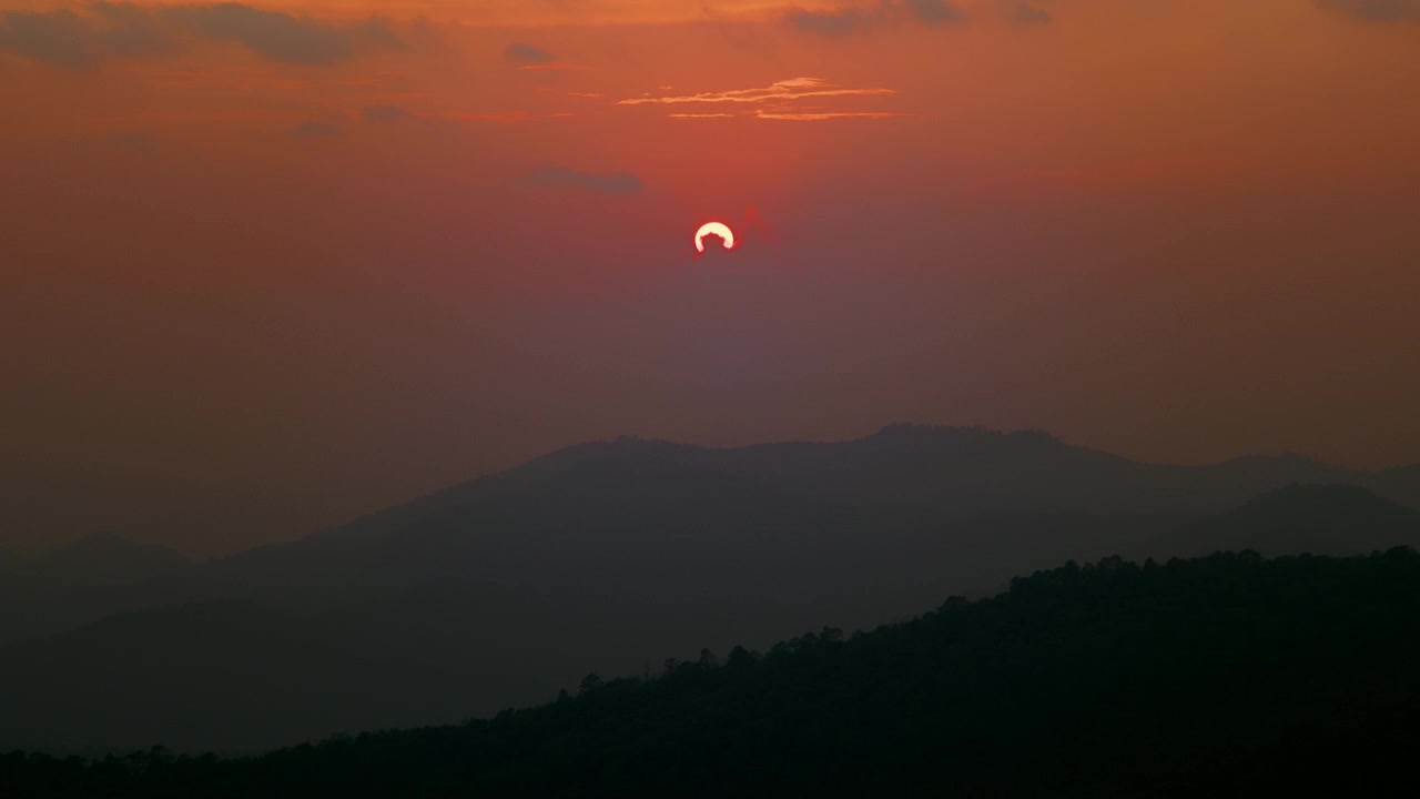 Solar Eclipse Setting Behind Mountain Silhouette at Sunset