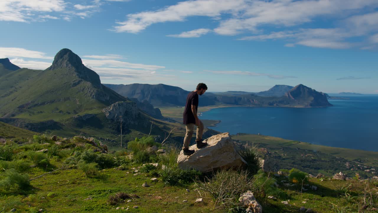 Man standing on a rock overlooking a stunning coastal landscape in Sicily