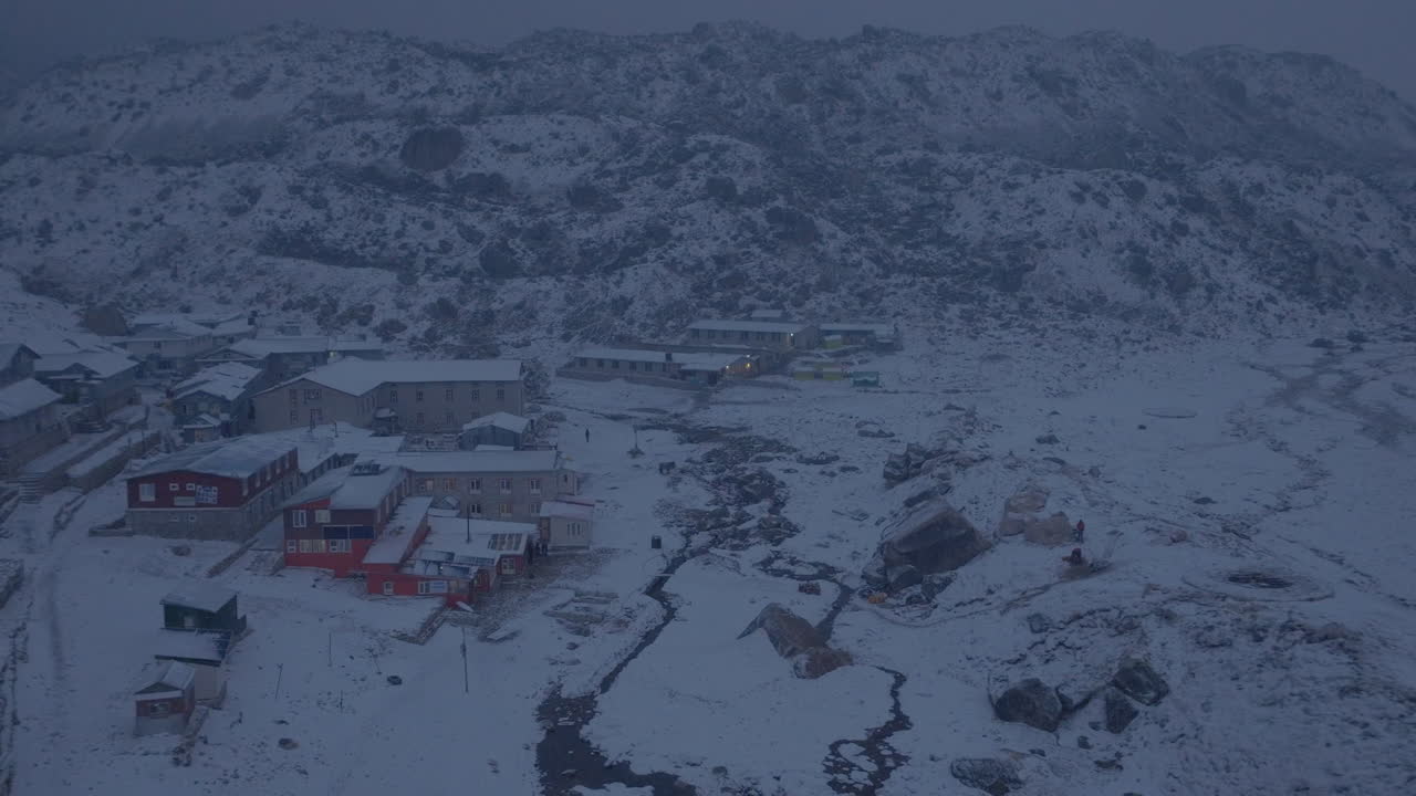 Everest Ana Kampı yürüyüşünde, Nepal, Khumbu'daki Lobuche köyünün havadan drone çekimi. Kar yağışı ve kara bulutlar, iklim krizini, düzensiz havayı ve korumayı işaret ederek yüksek rakımlı yerleşimi örtüyor