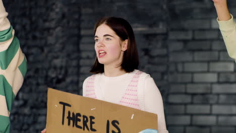 young environmental activist holding a cardboard with there is no planet b" inscription and protesting with her friends against climate change inaction"