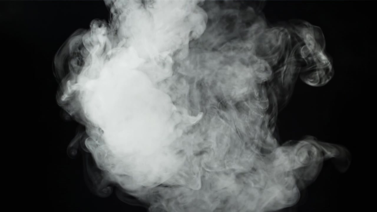 Humo blanco denso elevándose y extendiéndose sobre fondo negro