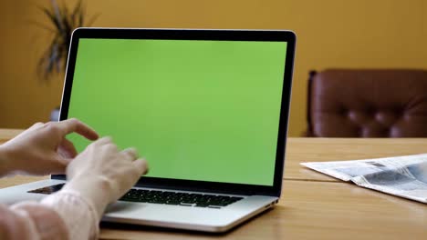 woman working on a laptop with a green screen