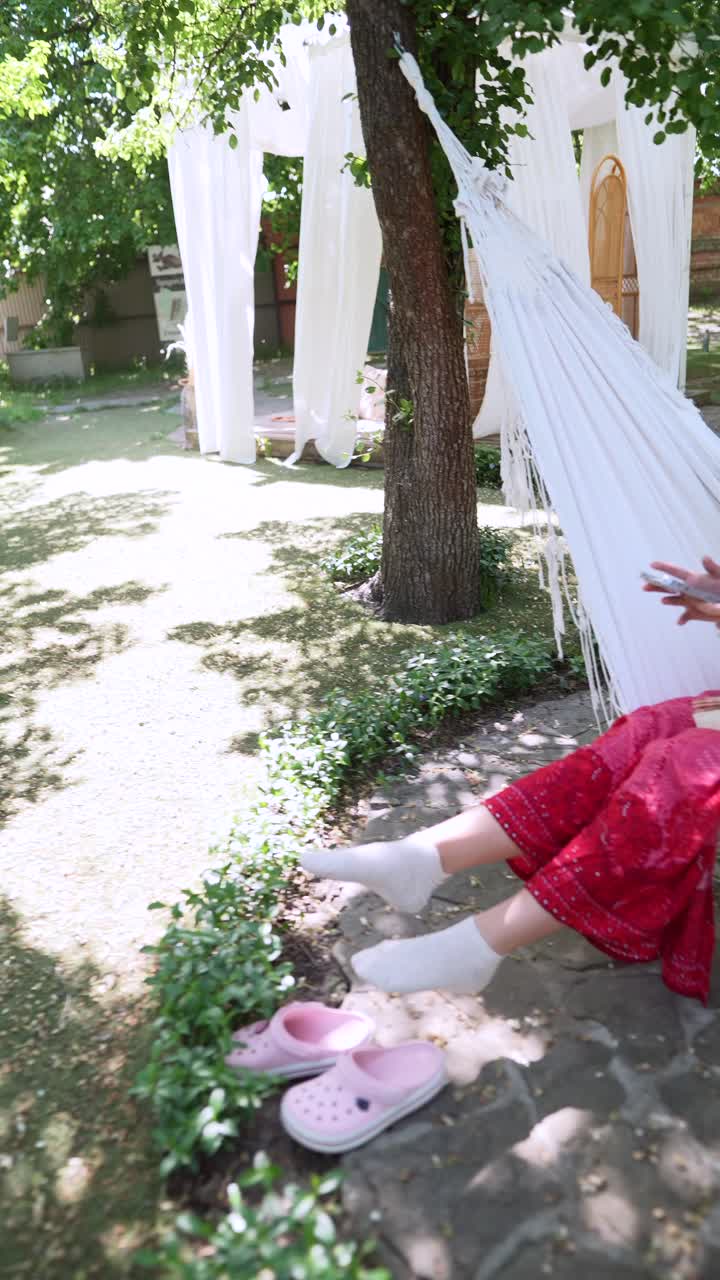 mujer joven relajándose en una hamaca en un jardín