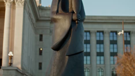 tilt up shot of the as long as the water flows statue on the grounds of the oklahoma state capitol building to the capitol building