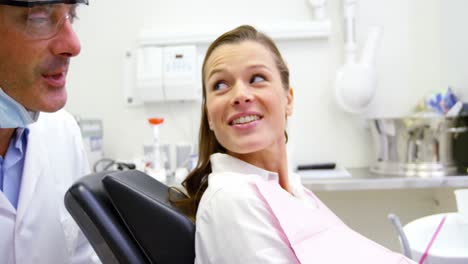 Smiling-dentist-talking-to-female-patient