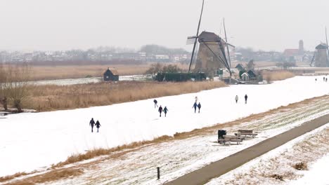 snowy dutch landscape with windmills and people