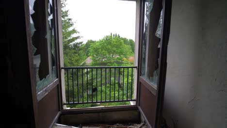 Vista-De-La-Naturaleza-Desde-Una-Habitación-De-Hotel-Abandonada-A-Través-De-Una-Ventana-Perdida-En-Francia-En-Cámara-Lenta