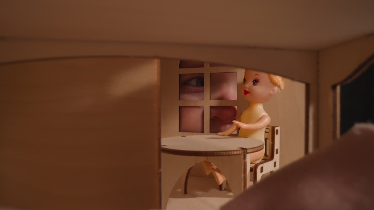 작은 아이의 파란 눈이 인형집의 창문을 통해 들여다본다.