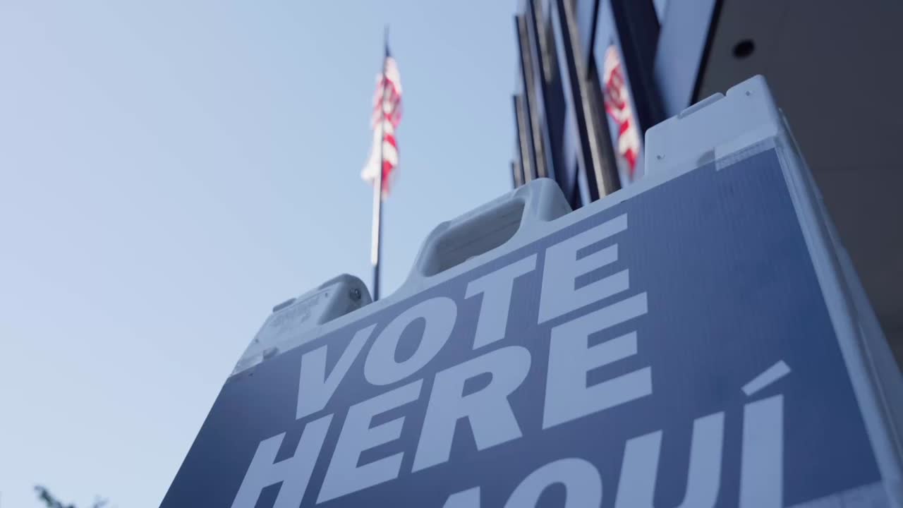 Vote here sign with an American Flag in the background
