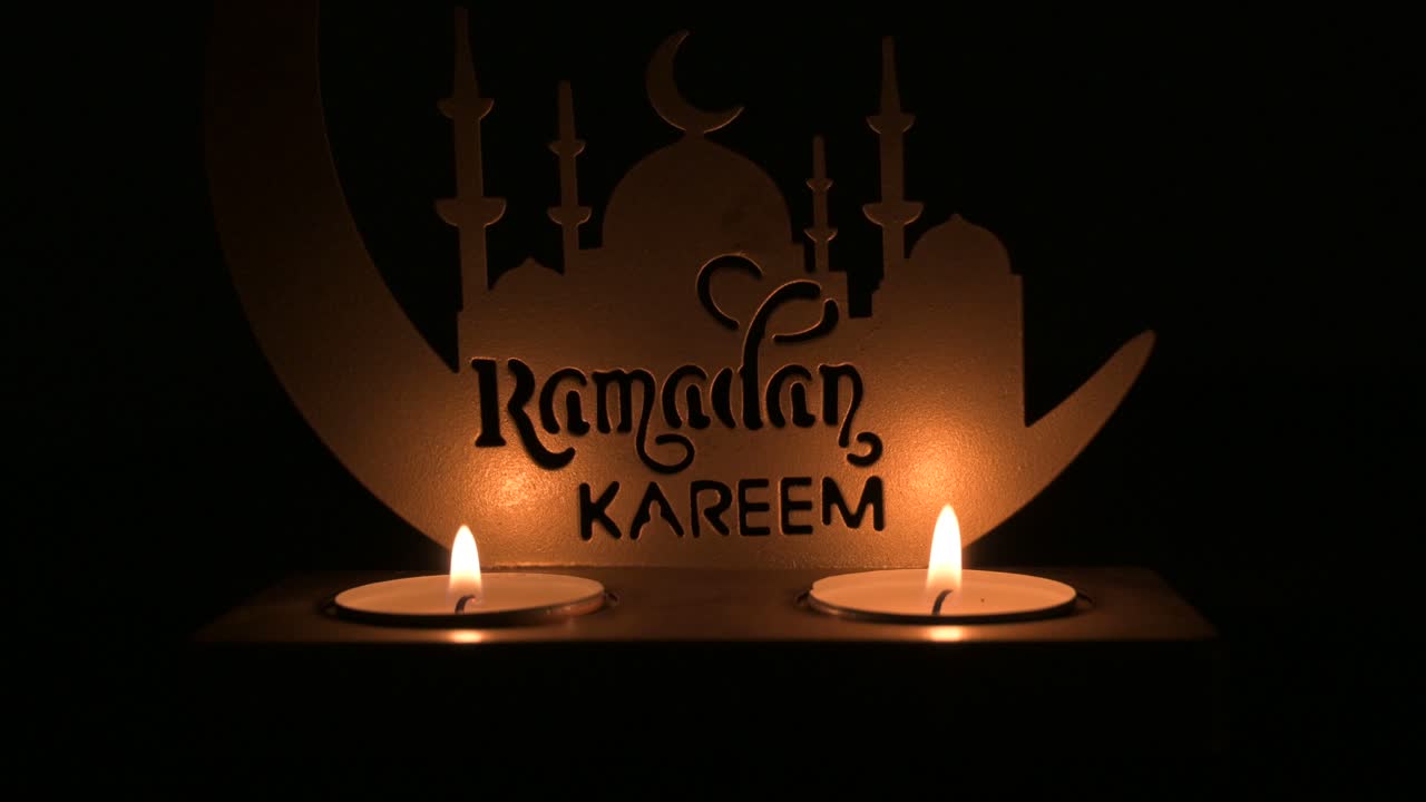 Ramadan-Kareem-Schild mit Moscheen-Silhouette, während Teelichtkerzen sanft verblassen