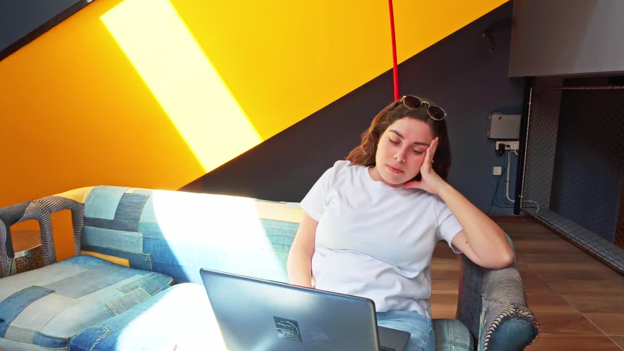 Woman working remotely on laptop in modern lobby