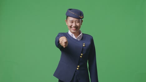 asian woman air hostess smiling and touching her chest then pointing at you while standing in the green screen background studio