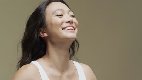 Happy-asian-woman-with-dark-hair-on-beige-background-with-copy-space,-slow-motion