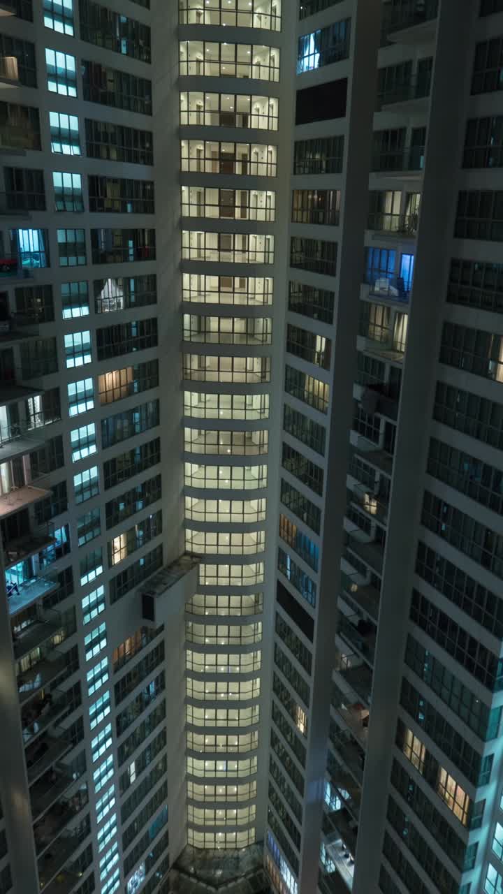 Vista Vertical de um Arranha-céu Moderno com Janelas Iluminadas à Noite