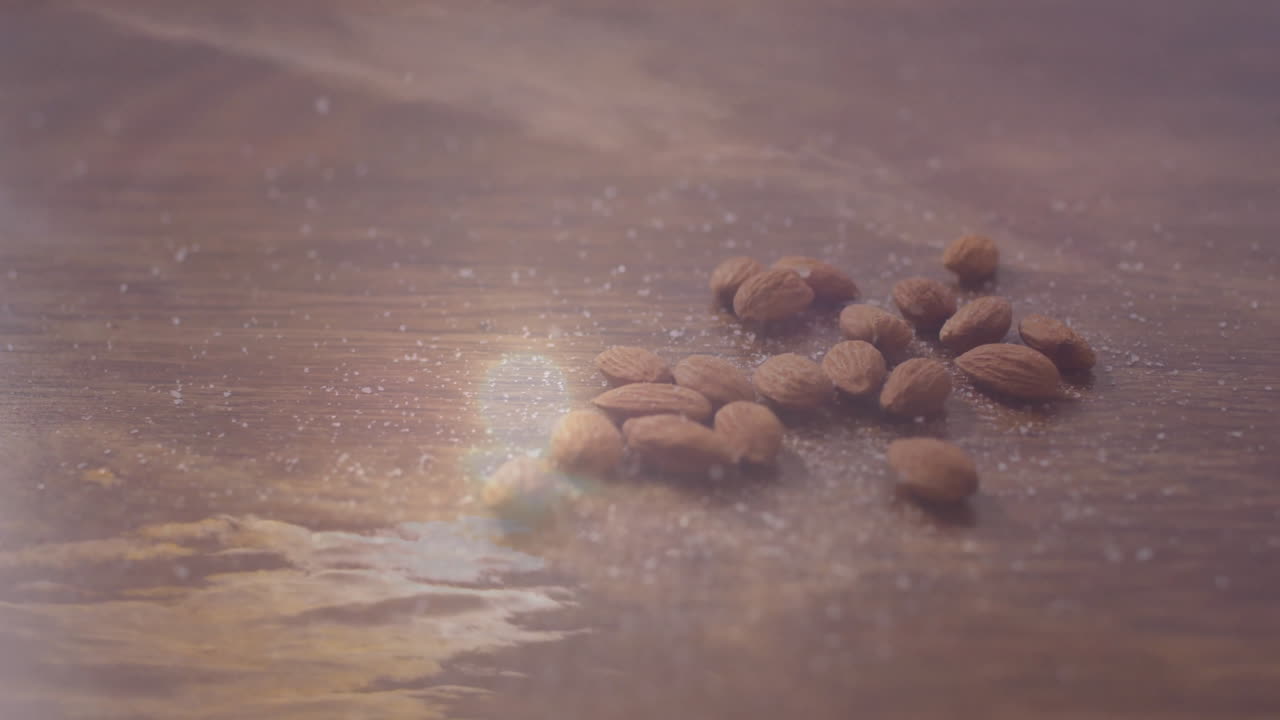 Scattered almonds on wooden surface with soft light creating reflections