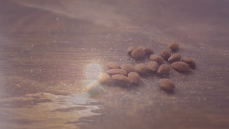 scattered almonds on wooden surface with soft light creating reflections
