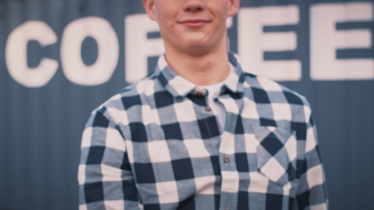 мужчина-работник, держащий чашку с напитками на вынос, стоящий перед контейнером с надписью "кофе"