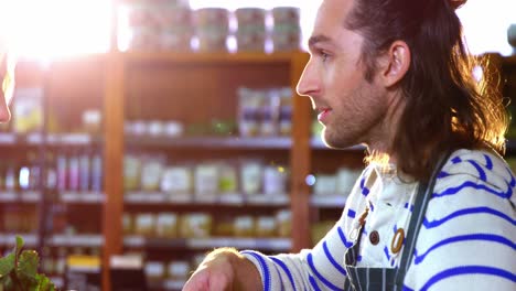 Male-staff-assisting-woman-in-selecting-fresh-vegetables