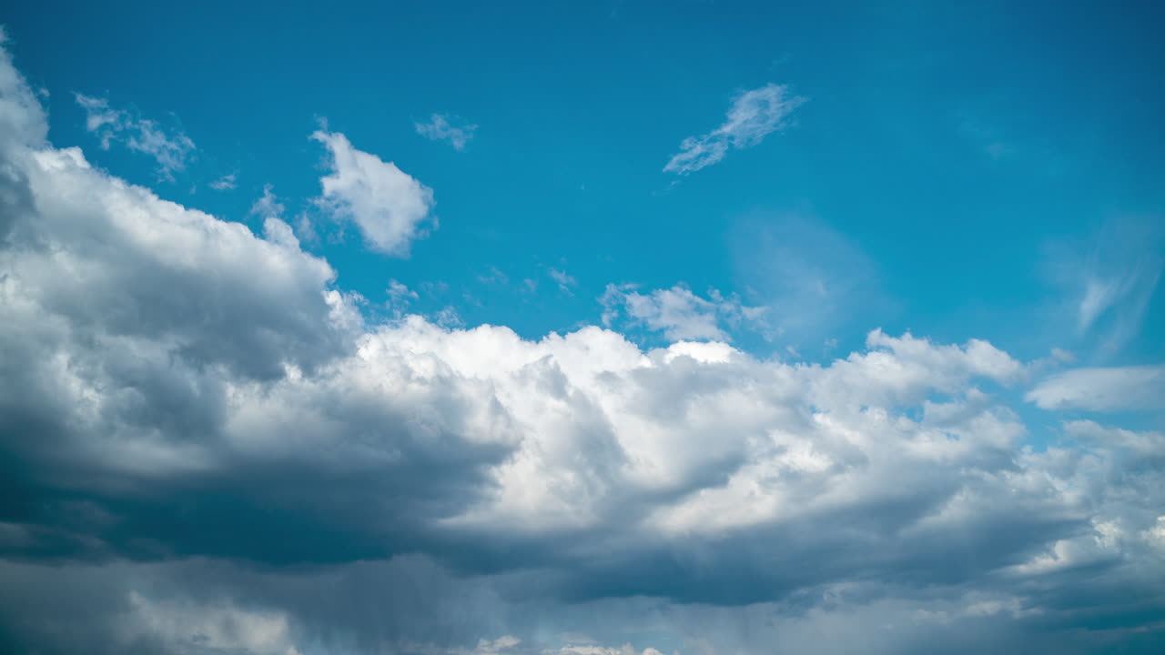 Rainy white clouds move in a blue sunny sky. Timelapse of cumulus clouds