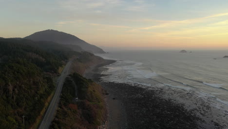 Vista-Aérea-De-La-Carretera-De-La-Costa-De-Oregon-Pasando-Por-El-Parque-Estatal-Humbug-Mountain-En-Una-Puesta-De-Sol