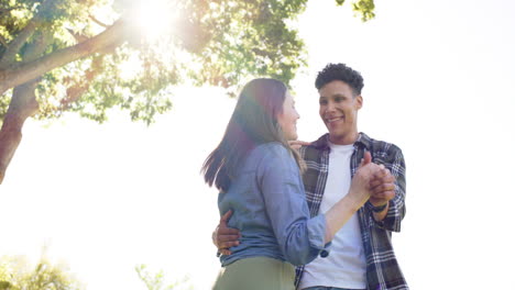 Happy-diverse-couple-dancing-in-sunny-garden,-in-slow-motion