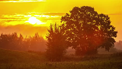 orange sun rising behind the clouds over countryside