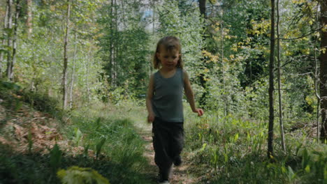 tomboy runs on track through remote woodland in summer, frontal backward dolly