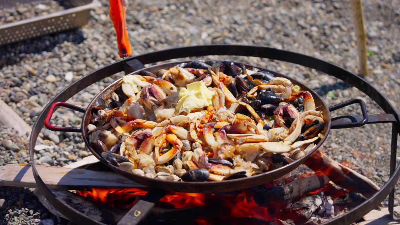 Seafood cooking over an open fire outdoors, with sizzling heat, rising smoke, and rustic flavors in a natural setting. Ideal for culinary, outdoor cooking, and food preparation footage