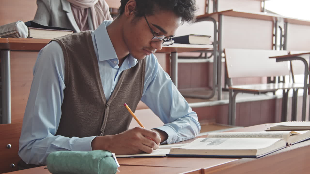 Excellent Mixed Race Male Student Taking Notes in Copybook